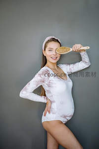 俏皮孕妇手持梳子遮眼微笑