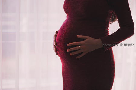 红裙孕妈侧身凝视孕肚