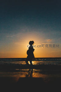 夕阳下海边孕妇剪影漫步的诗意画面