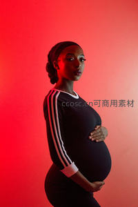 红光映衬下，孕妈侧身温柔抚肚