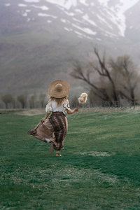 草帽少女奔跑在雪山下的绿野中
