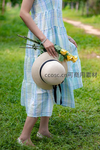 草地上的温柔时刻：手握草帽与黄玫瑰的背影