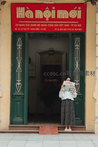 女子门前读报，红牌绿门映古韵