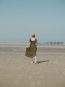 海边漫步的花裙女子背影