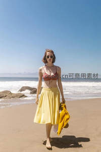 海滩漫步穿黄裙戴墨镜的女子