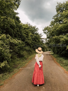红裙女子背影漫步林荫小路