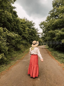 红裙草帽女子独行乡野小径
