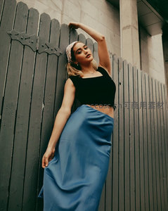 蓝裙女子倚靠木栅栏