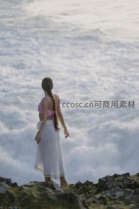 海边岩石上凝望浪花的女子背影