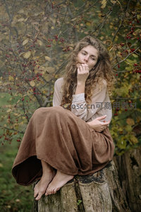 秋日树桩上沉思的卷发女子