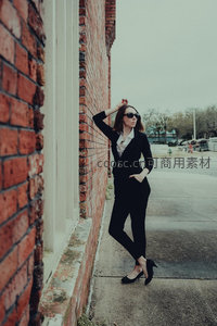红砖墙边的时尚女性姿态