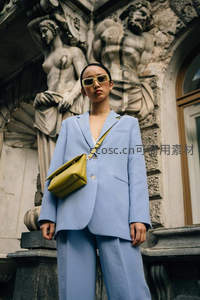 蓝西装女子立于古典雕塑前