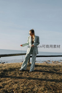 海边草地上，女性浅绿西装漫步