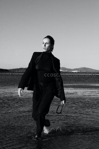 黑白影像中女子穿黑西装涉水前行