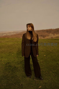 棕西装女子伫立秋日草地凝视远方