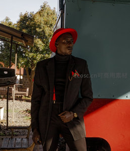 戴红帽男子倚靠火车头展现复古风范