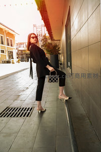 黑衣女子街边回眸，墨镜高跟包袋演绎都市摩登风