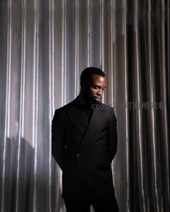 黑衣绅士垂首伫立光影帘幕前