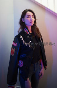 时尚女性身着刺绣夹克倚墙而立