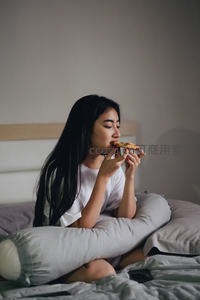 长发女子床上惬意享用披萨美食
