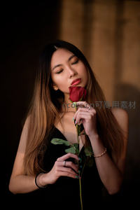 黑裙女子闭目轻嗅红玫瑰花瓣
