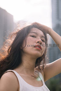 逆光长发女孩轻抚秀发，城市剪影衬托