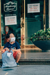 戴口罩小男孩街边台阶静坐等待