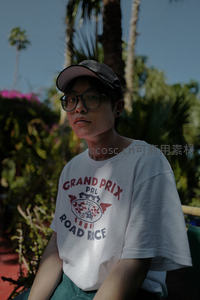 戴帽青年在热带植物前凝视镜头