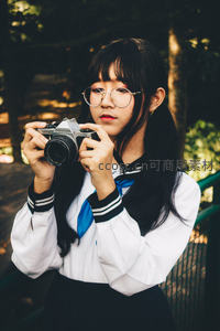 戴眼镜少女手持相机专注拍摄
