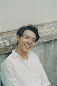 白墙前绽放灿烂笑容的帅气青年