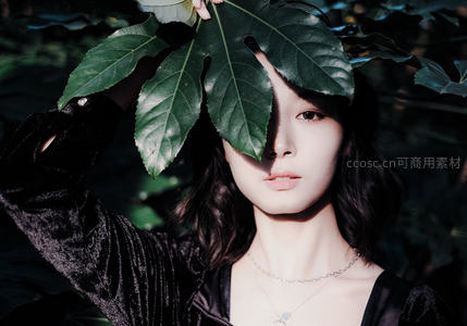 黑衣女子手持绿叶遮面特写