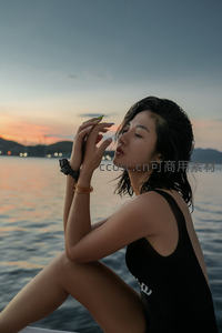 夕阳海景中黑衣女子闭目养神