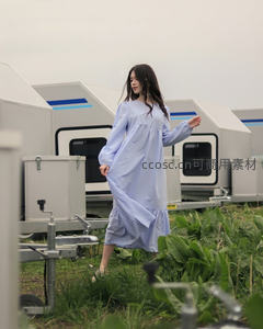 蓝裙少女漫步田园，现代房车与绿植相映成趣