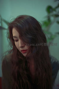 柔光下卷发女子低头沉思