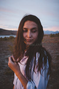 暮色荒野，少女轻抚发丝凝视镜头