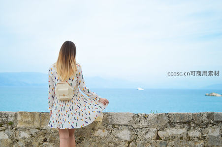 女子背影眺望蔚蓝大海，裙摆轻扬