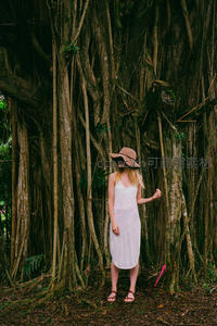 巨树根旁的白衣女子，戴帽凝望