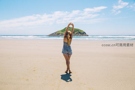 沙滩上女子背影伸展双臂拥抱海天