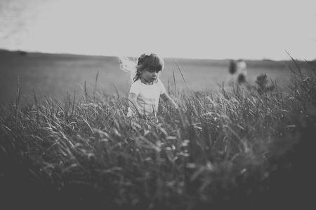 孩童穿行草丛中，黑白光影忆童年