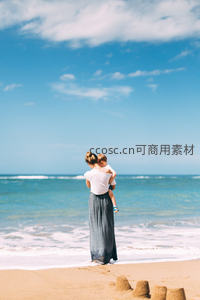 母子海边相拥，沙滩城堡见证温馨时光