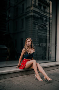 时尚女郎倚坐街边橱窗前摆拍