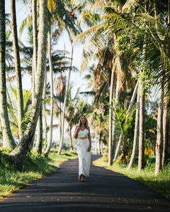 椰林小径上白衣女子漫步度假