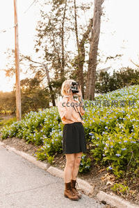 花丛旁少女手持复古相机拍摄