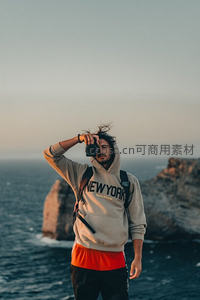 悬崖边摄影师迎风拍摄海景