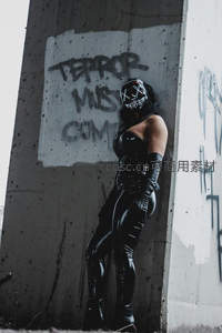 涂鸦墙边戴格栅面具的酷女孩