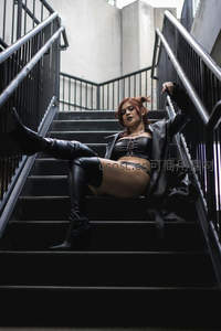 红发女子慵懒倚靠工业风楼梯