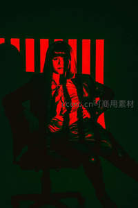 绿幕红光中，冷艳女郎坐姿霸气