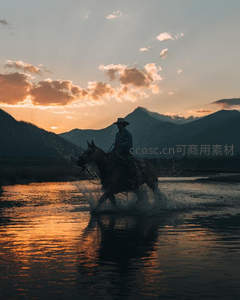 夕阳下骑士策马涉水剪影