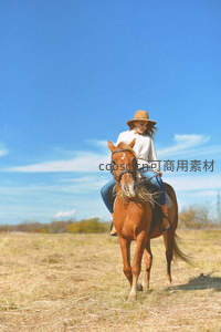 草原上戴帽女子悠然骑马享受晴空