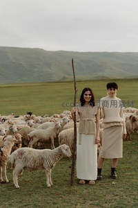 两位女子立于羊群中，手持木杖如牧者